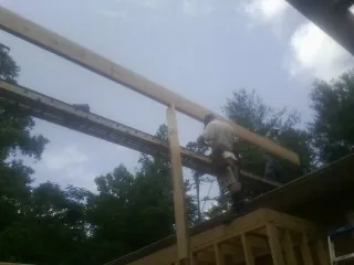 Carpenter setting a ridge beam over a new addition frame — Ice Dam Removal by Roofing Brothers in Peapack