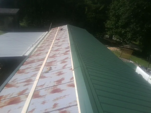 Old rusted panels beside newly installed green metal roofing — Wind Damage Roof Repair by Roofing Brothers in Peapack