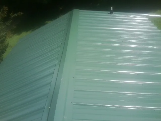 New green metal panels meeting at the ridge of a roof — Flat Roof Repair work by our crew in Peapack