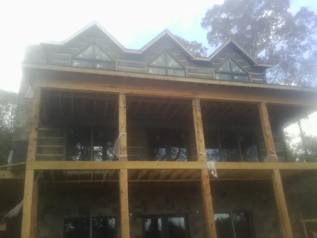 Dormers and porch framing on a large log home under construction — Roof Coating work by our crew in Peapack