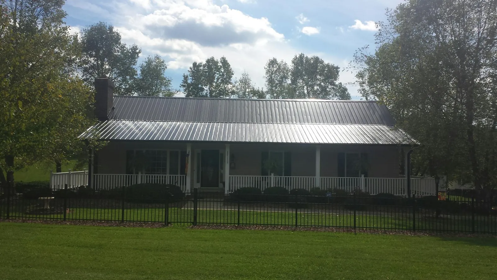 Gray metal roof on a brick ranch with a full width front porch — Gutter Guard Installation work by our crew in Peapack