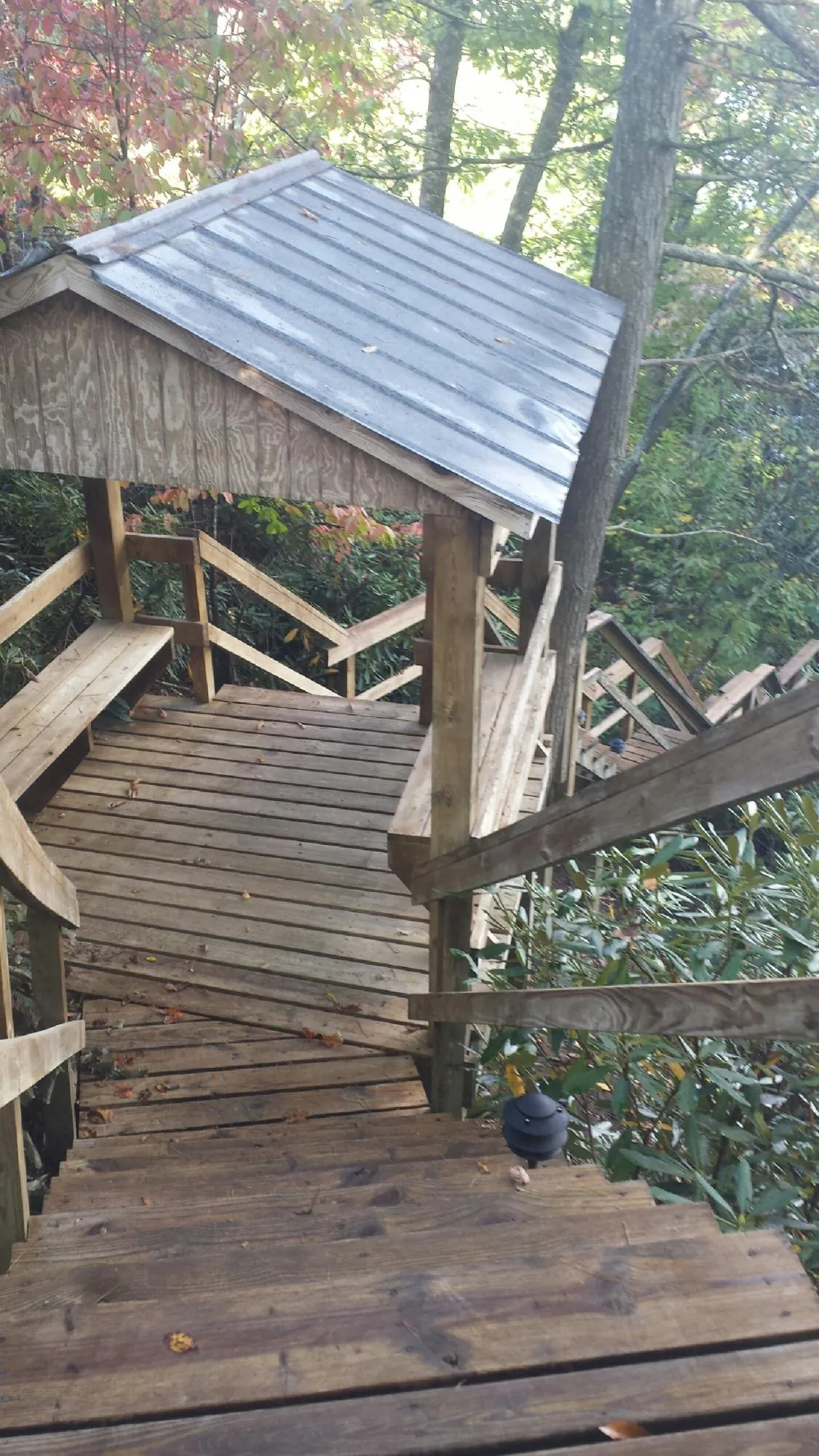 Metal roofed shelter over wooden steps on a wooded walkway — Skylight Repair & Installation work by our crew in Peapack