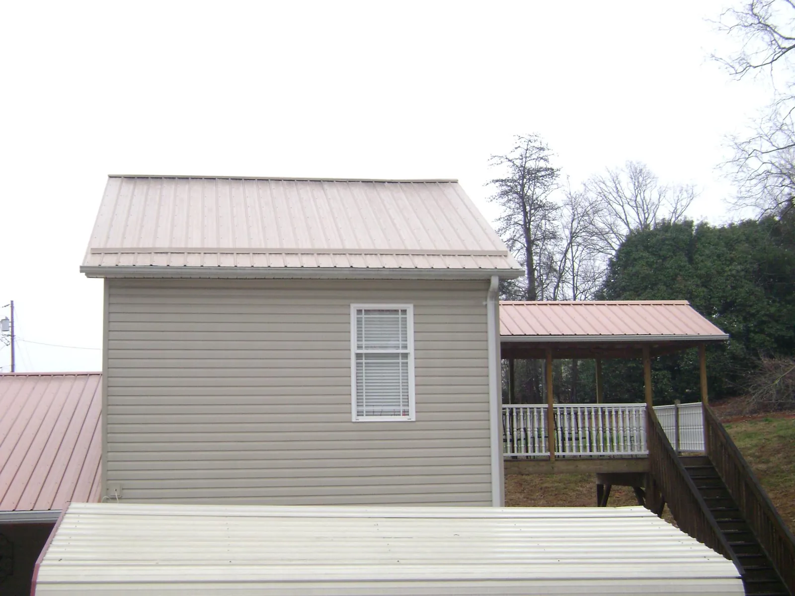 Tan metal roofs on a two story addition and attached porch, from a Roof Replacement job in Peapack