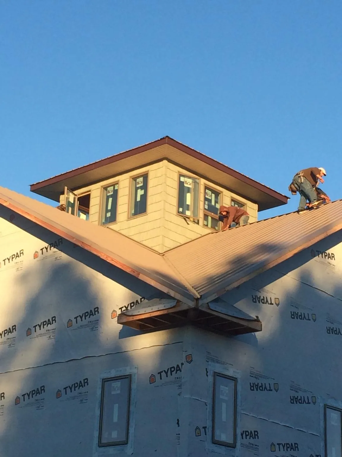 Roofers working around a rooftop cupola on a new metal roof at sunset — Roof Waterproofing in Peapack by Roofing Brothers